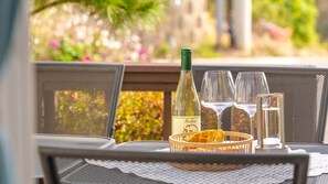Une table dressée avec une bouteille de vin, deux verres à vin, un petit panier contenant des gaufres et une bougie.