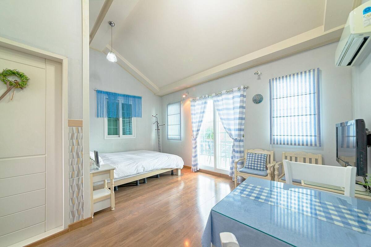 A bedroom with a bed, a desk, a chair, a radiator, and a television.