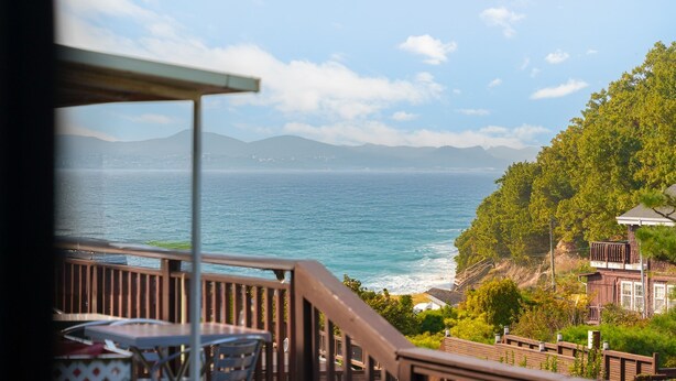 Un balcón con vista al mar y a las montañas.