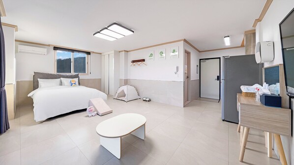 Habitación de hotel con cama, escritorio, silla, mesita, tienda de campaña, puerta y ventana.