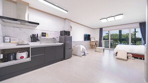 Cocina moderna con estufa incorporada, microondas y refrigerador. Hay una tienda de campaña montada en la zona de estar, y una cama con vistas al exterior.