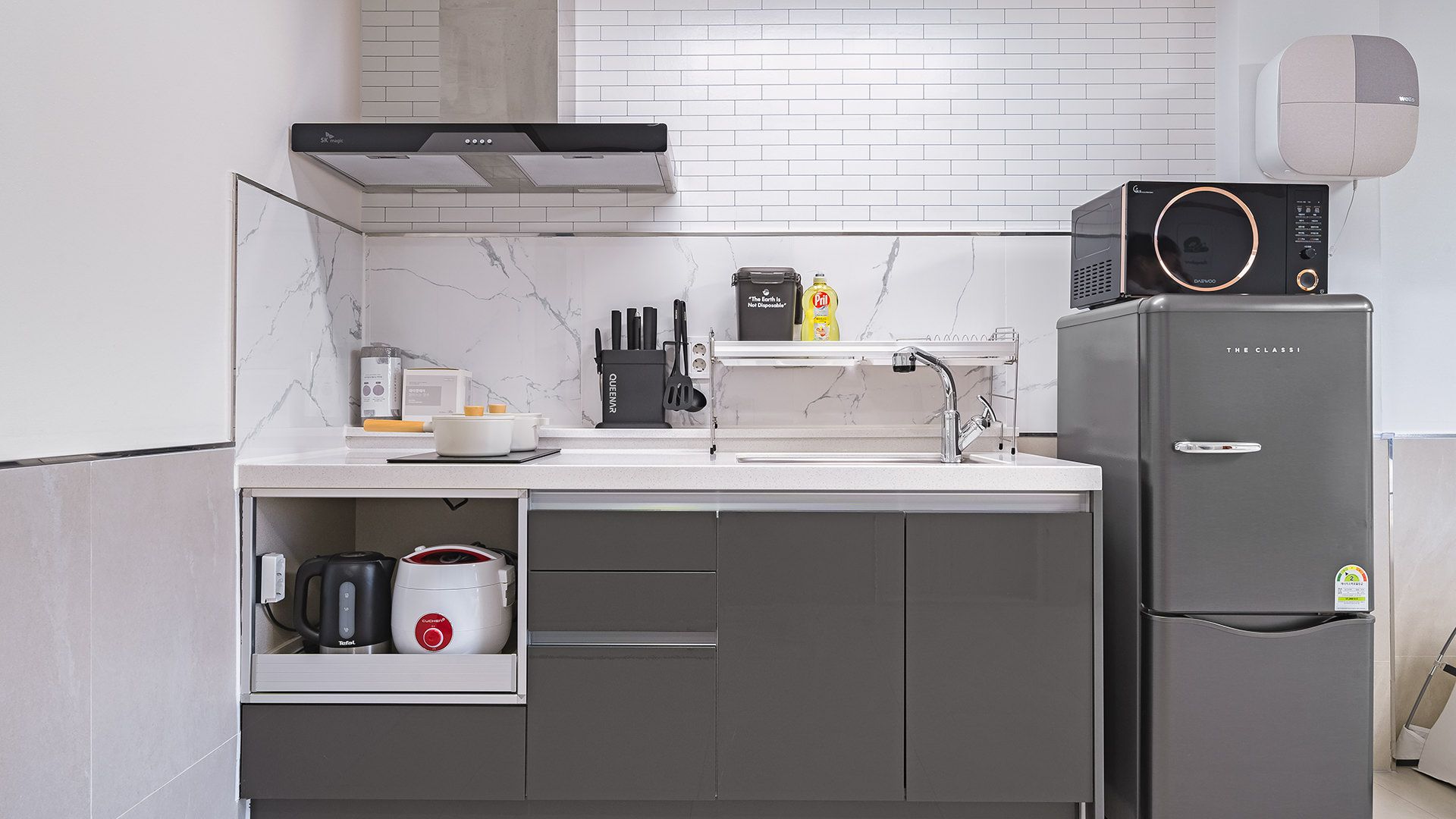 Una cocina moderna con horno integrado, cafetera y refrigerador.