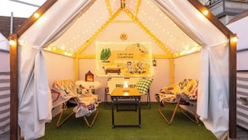 Una carpa acogedora con una mesa y sillas, un farol y un letrero que dice 'Let's go camping'.