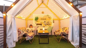 Una tenda acollidora amb taula i cadires, un fanal i un cartell que diu 'Let's go camping'.