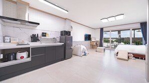 Cocina moderna con horno integrado, microondas y refrigerador. Hay una tienda de campaña montada en la sala de estar, y una cama con vistas al exterior.