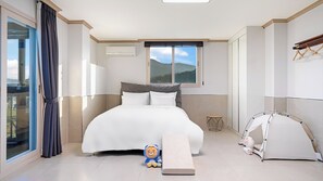 A hotel room with a bed, a window with a view of the outdoors, a small table, and a tent-like structure.