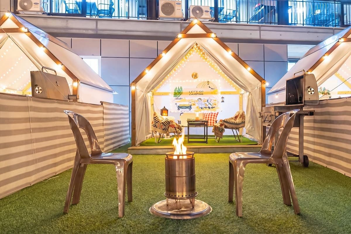 A camp-themed area with tents, a campfire, and camping chairs.