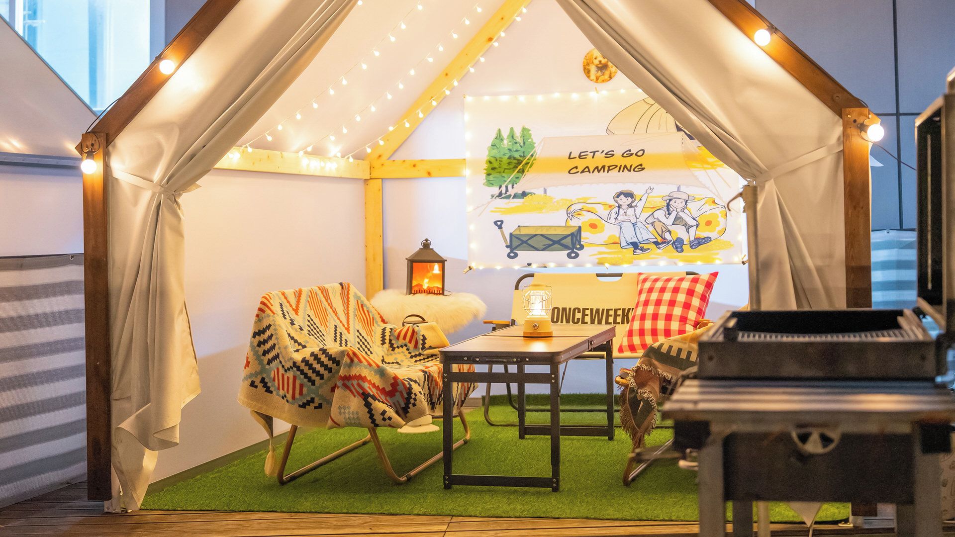 A cozy indoor camping setup with a tent, a rocking chair, a table, and a piano.