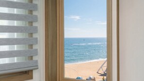 A window view of a beach with a chair and a hat on the sand. - Sokcho Harmony Pension (Sokcho)