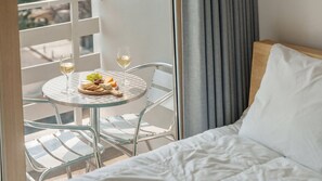 A hotel room with a bed, a balcony with a table and chairs, and a view of the outside. - Sokcho Harmony Pension (Sokcho)