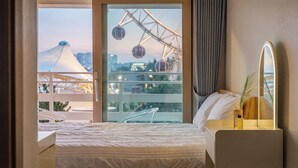 A hotel room with a bed, a bedside table with a mirror, and a view of a Ferris wheel. - Sokcho Harmony Pension (Sokcho)