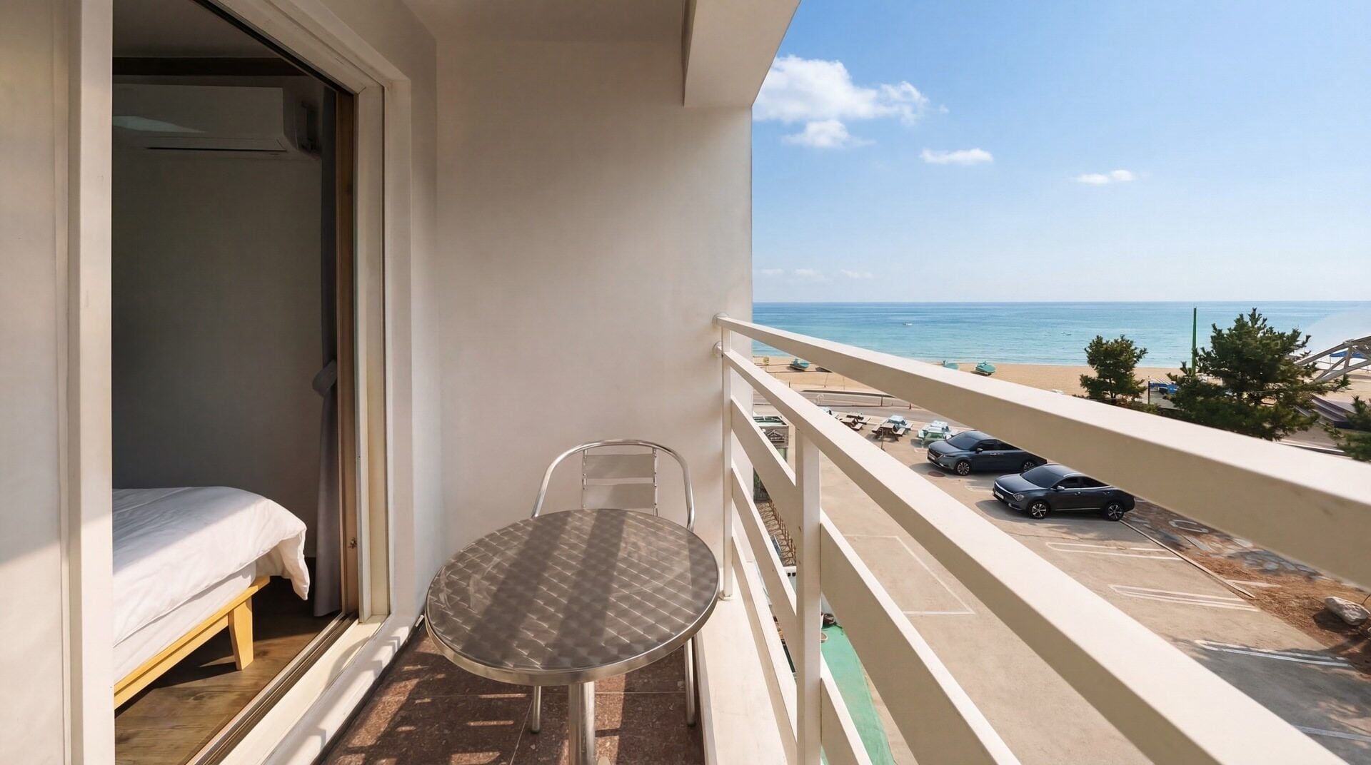 Un balcón con cama, mesa y vistas a la playa y al océano.