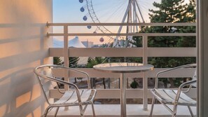 A balcony with two metal chairs and a small round table, overlooking a Ferris wheel and trees. - Sokcho Harmony Pension (Sokcho)