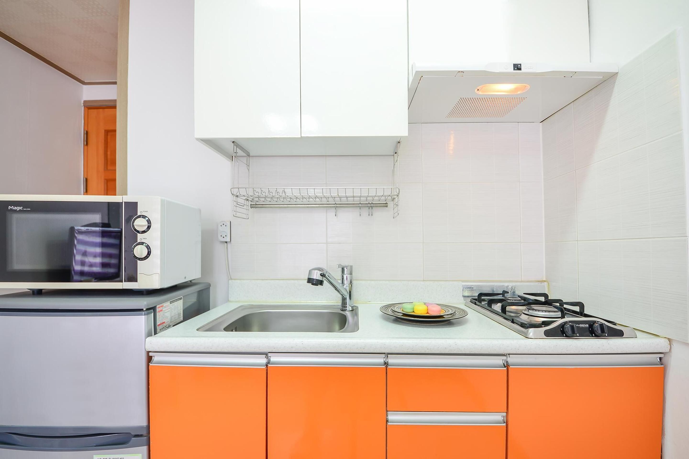 A compact kitchen with a microwave, a small refrigerator, a sink, and a gas stove.