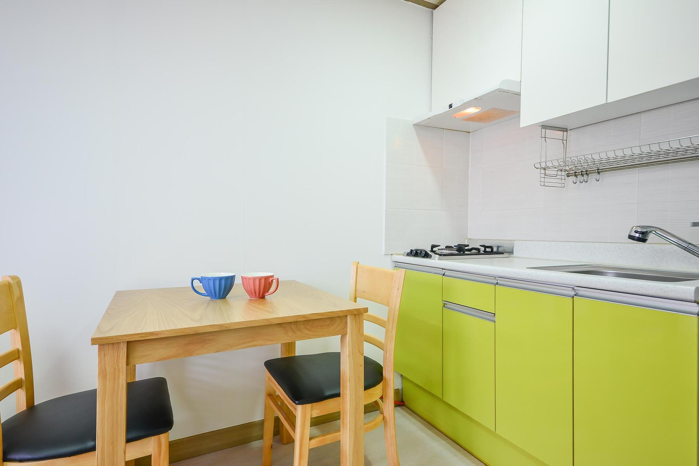 A compact kitchen with a wooden table and chairs, a gas stove, and green cabinets.