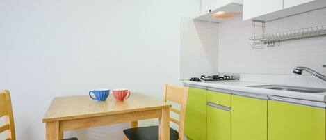 A compact kitchen with a wooden table and chairs, a gas stove, and green cabinets.
