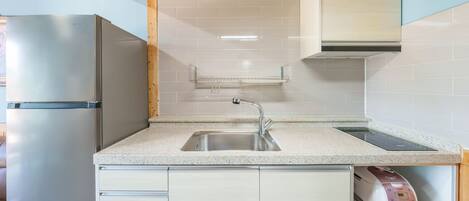 A modern kitchen with a stainless steel refrigerator, a sink with a sleek faucet, and a built-in oven.