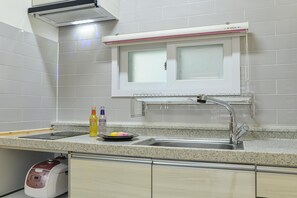 A kitchen with a stainless steel sink, a window with frosted glass, a dish rack, and a rice cooker. - Samcheok Healingcamp Pension (Samcheok)
