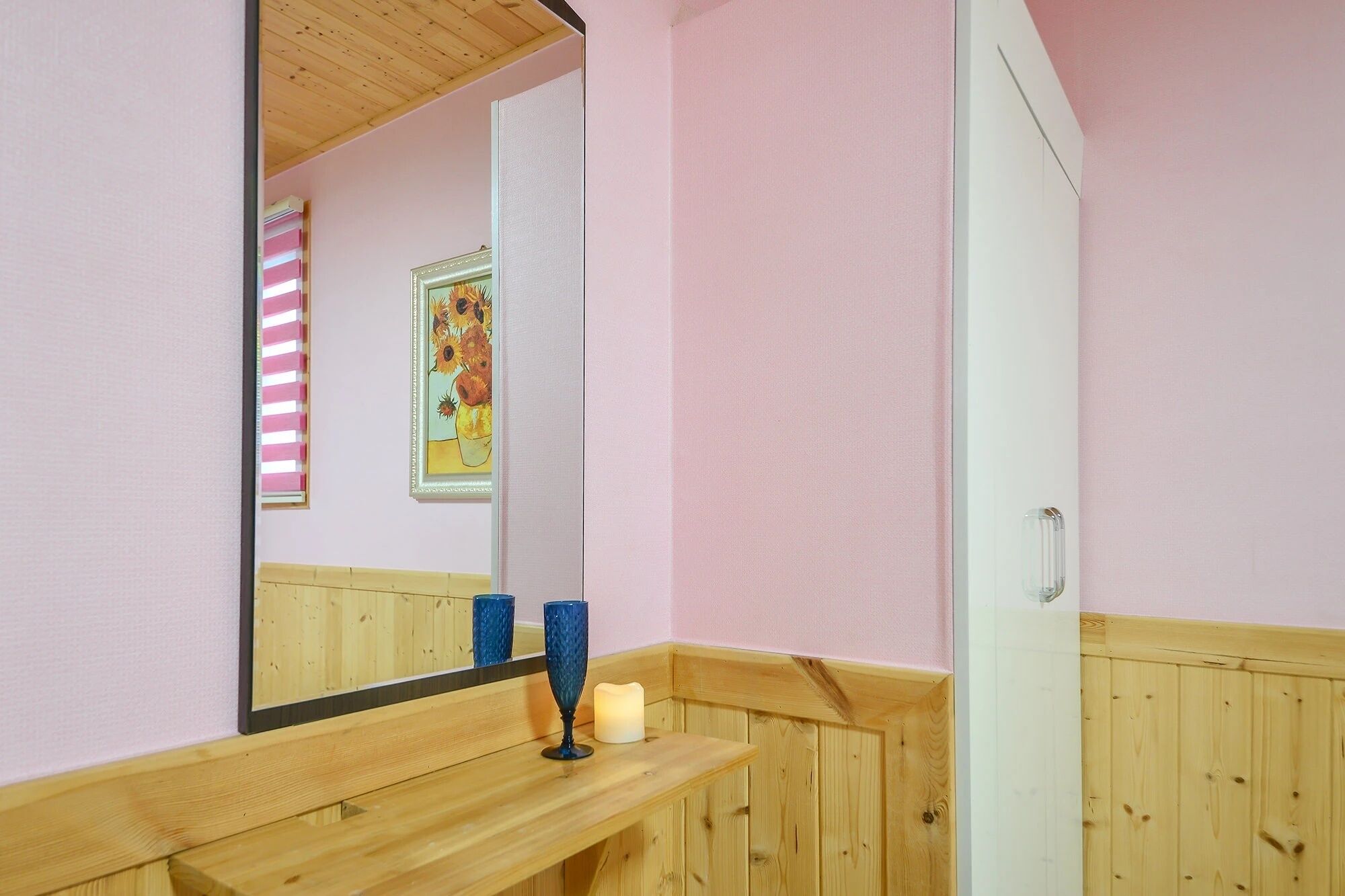 A bathroom with a wooden vanity, a mirror, and a framed artwork on the wall.
