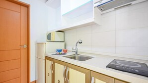 Una cocina equipada con microondas, lavabo y cocina por inducción.