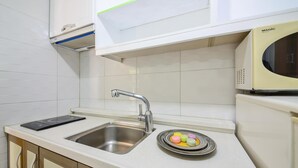 Una cocina con un lavamanos de acero inoxidable, un microondas y un plato con macarons de colores.