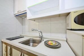 A kitchen with a stainless steel sink, a microwave, and a plate with colorful macarons. - Geoje Purenneoul Pension (Geoje)