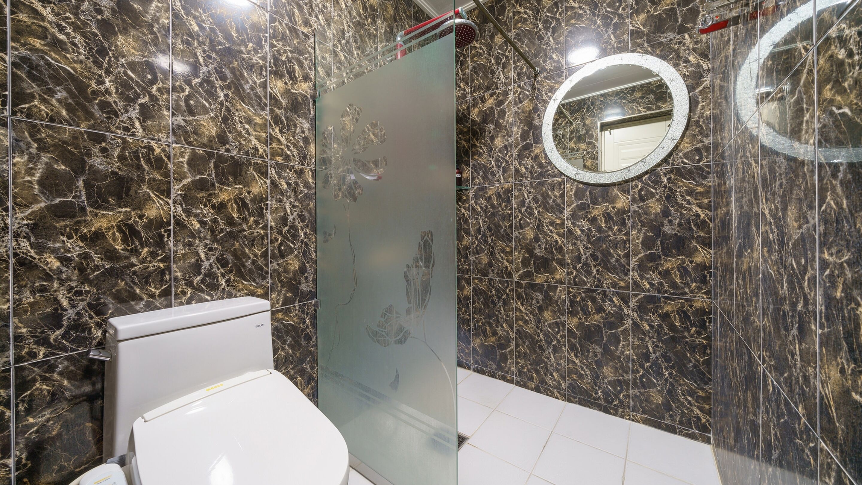 A bathroom with a toilet, a shower, and a mirror.