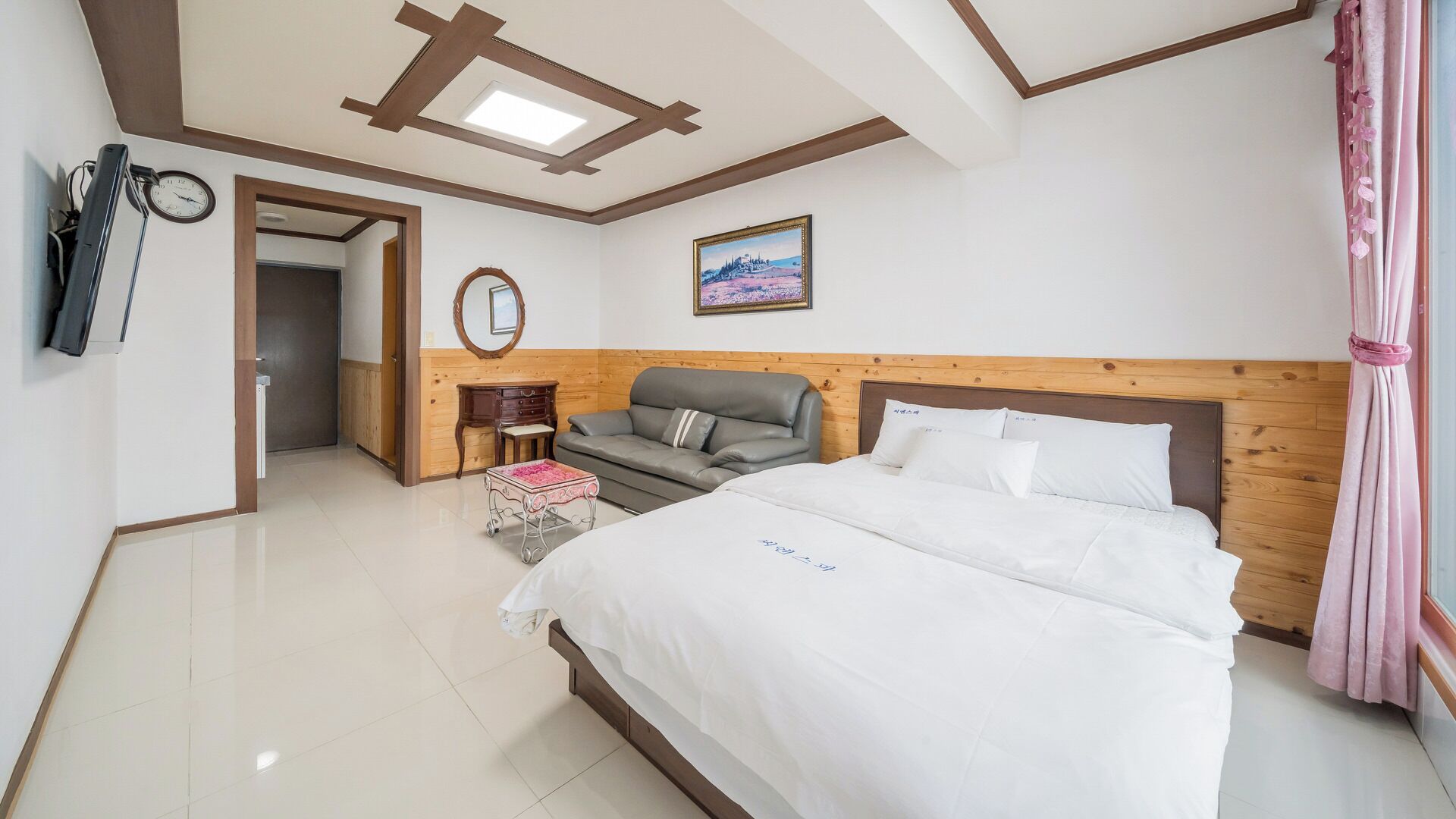 Habitación de hotel con cama, sofá, una mesita, un espejo y un cuadro en la pared.