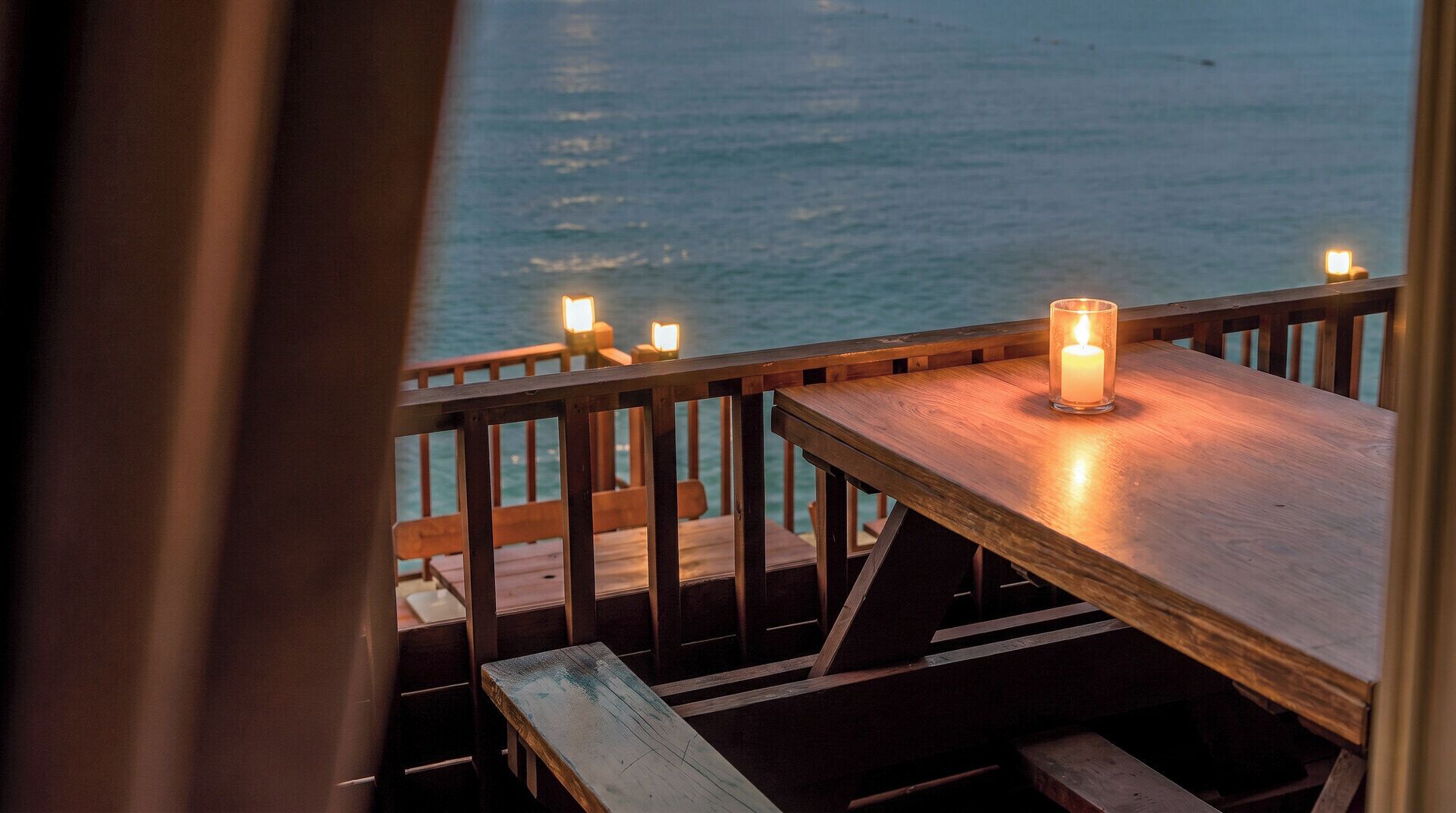 A wooden deck with a table and benches, overlooking a body of water.