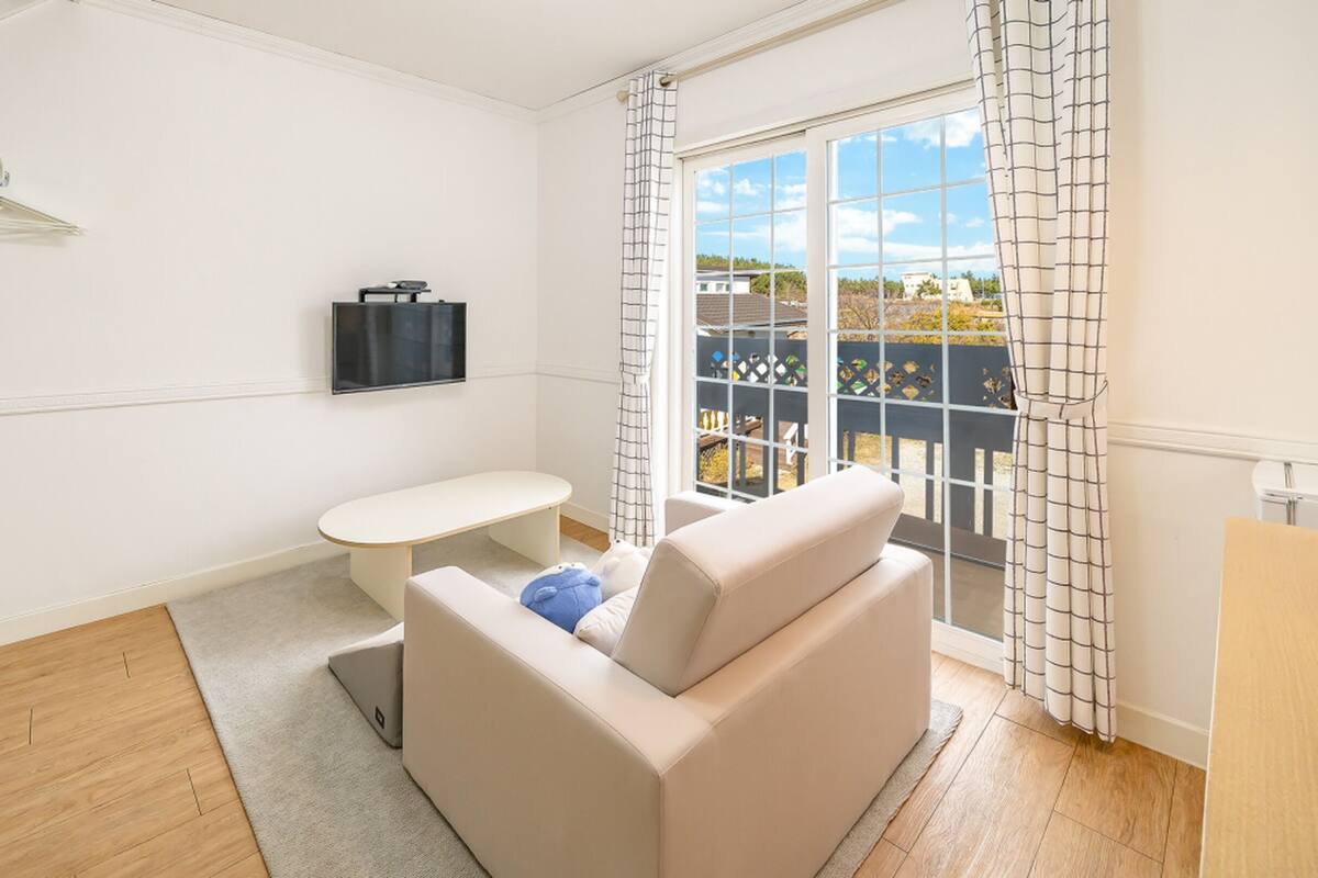 Une pièce moderne et minimaliste, avec un canapé, une petite table et un téléviseur fixé au mur.