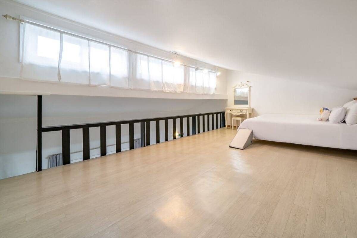 Une chambre à coucher avec un lit, un bureau, un miroir et un balcon.