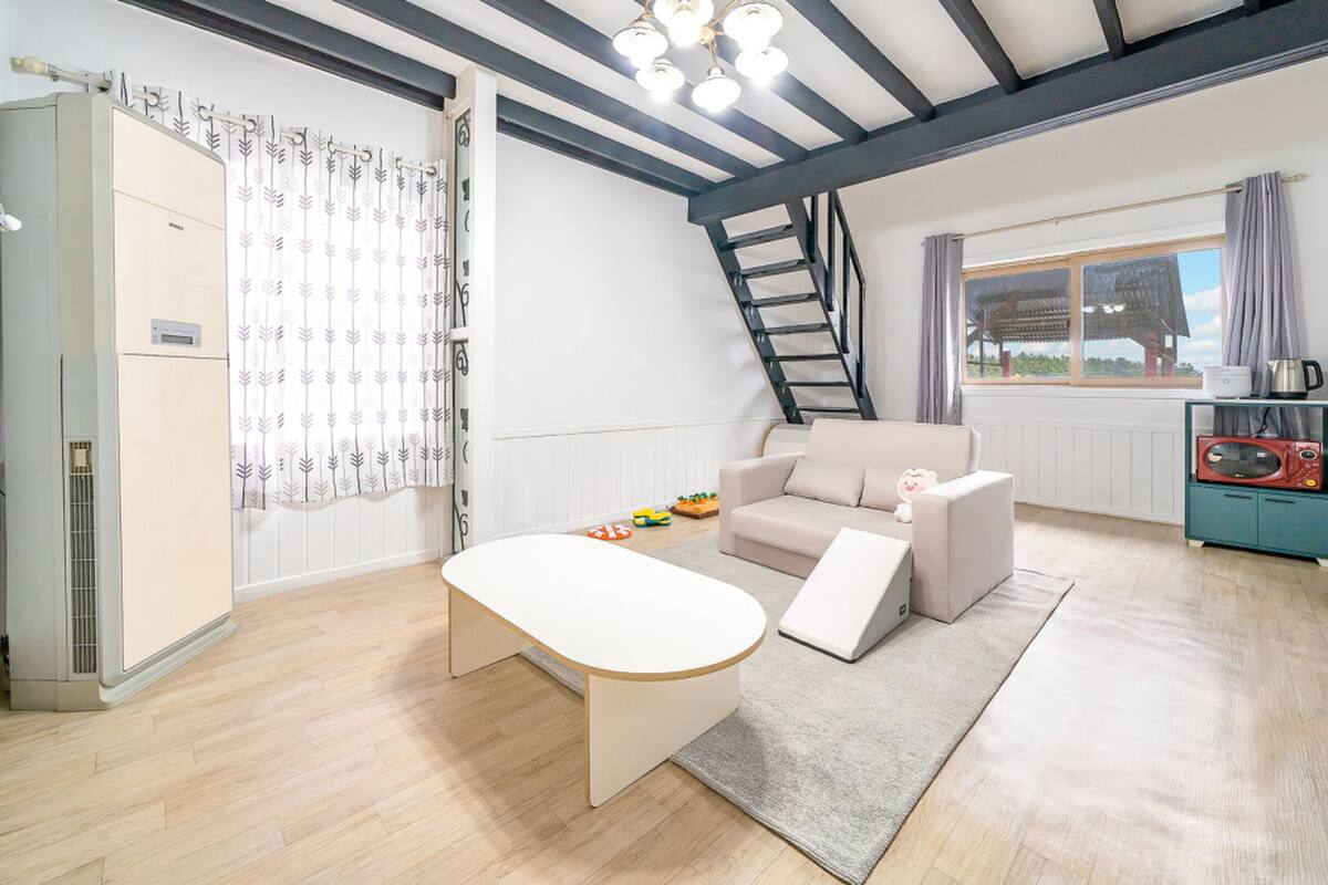 Un appartement moderne doté d’un espace de vie de style « loft », d’une cuisine équipée d’un four à micro-ondes et d’un coin repas avec une table et des chaises.