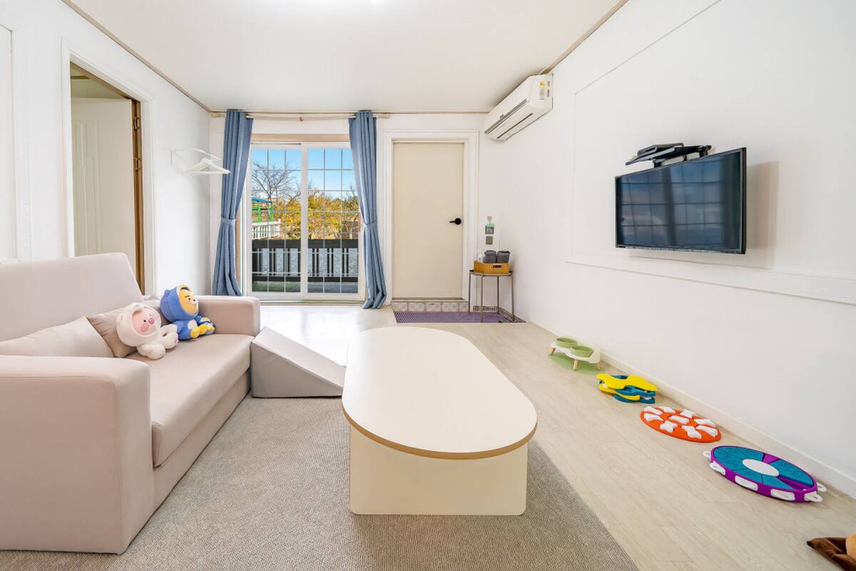 Un salon moderne avec un canapé, une table basse et un téléviseur fixé au mur.