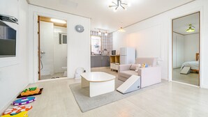 Un apartamento moderno y bien iluminado con kitchenette, un baño y una sala de estar con sofá y una mesita.