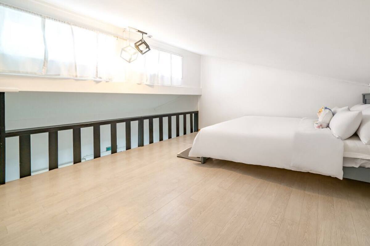 Une chambre à coucher avec un lit, une fenêtre et une rambarde.