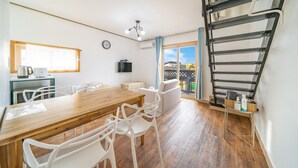 Una cocina moderna con una mesa de madera y sillas blancas, estufa integrada y una ventana con cortinas.