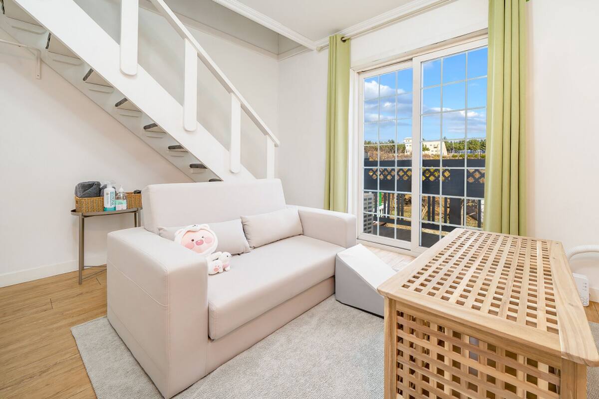 Un salon moderne avec un canapé blanc, une table en bois et un escalier.