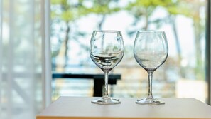 Two clear glass wine glasses on a white table against a blurred background of trees and a building. - Yeosu Dangdangi Dog Family Pension Gold (Yeosu)