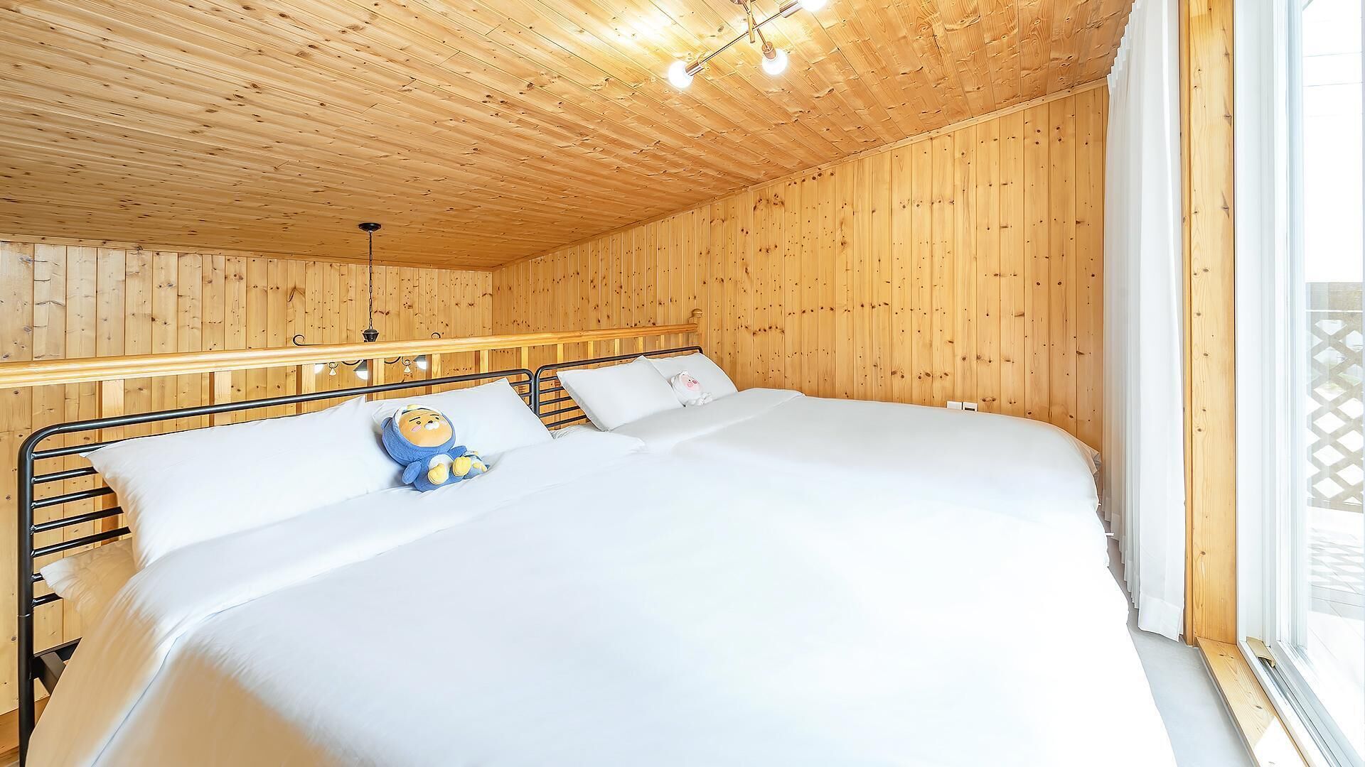 A wooden-paneled room with a bed, a hanging light fixture, and a window.