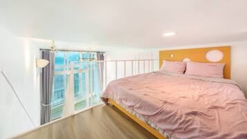 A bedroom with a large bed, a wooden headboard, and a balcony with curtains.