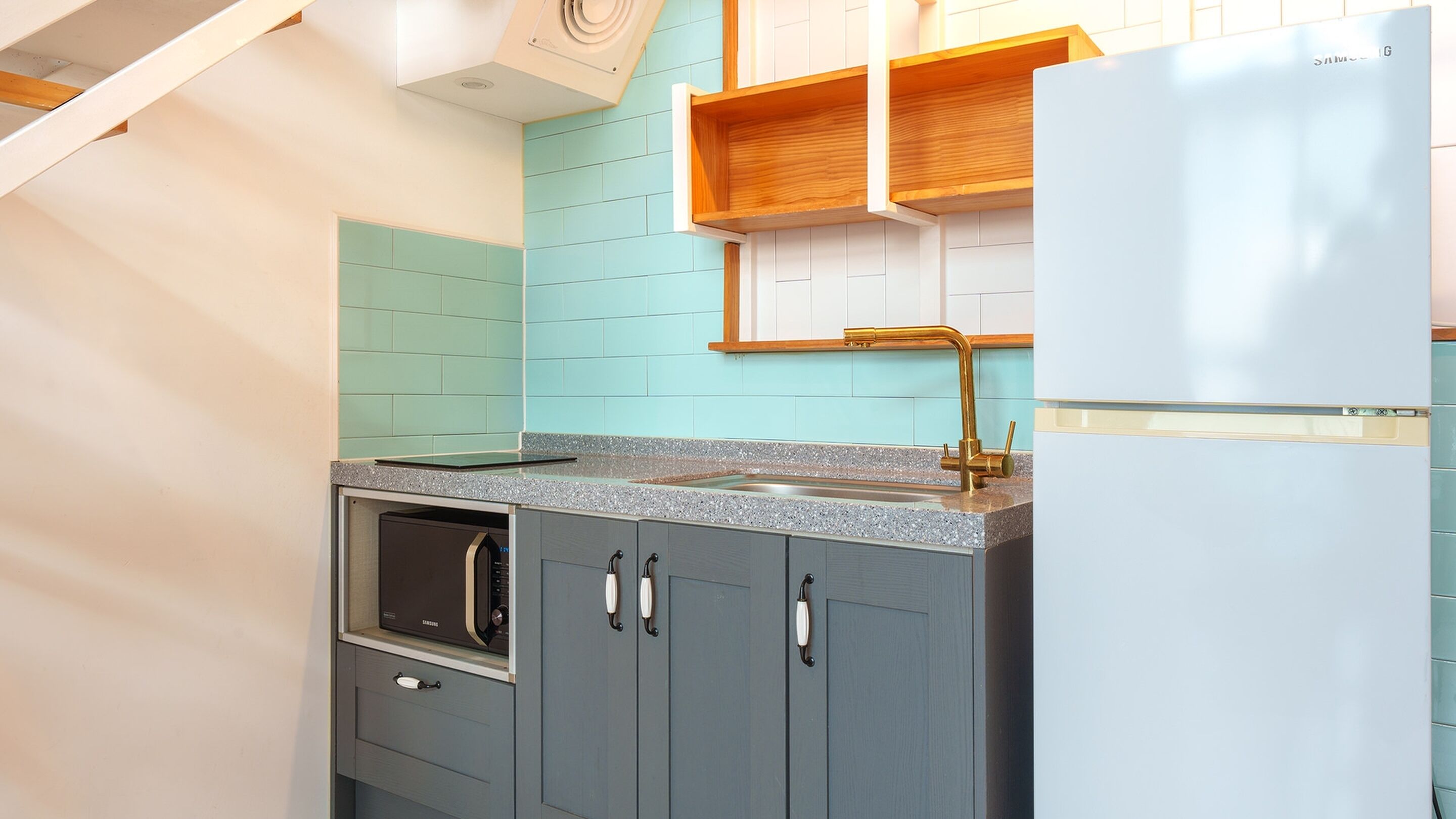 A kitchen with teal tiles, a stainless steel oven, and a white refrigerator.