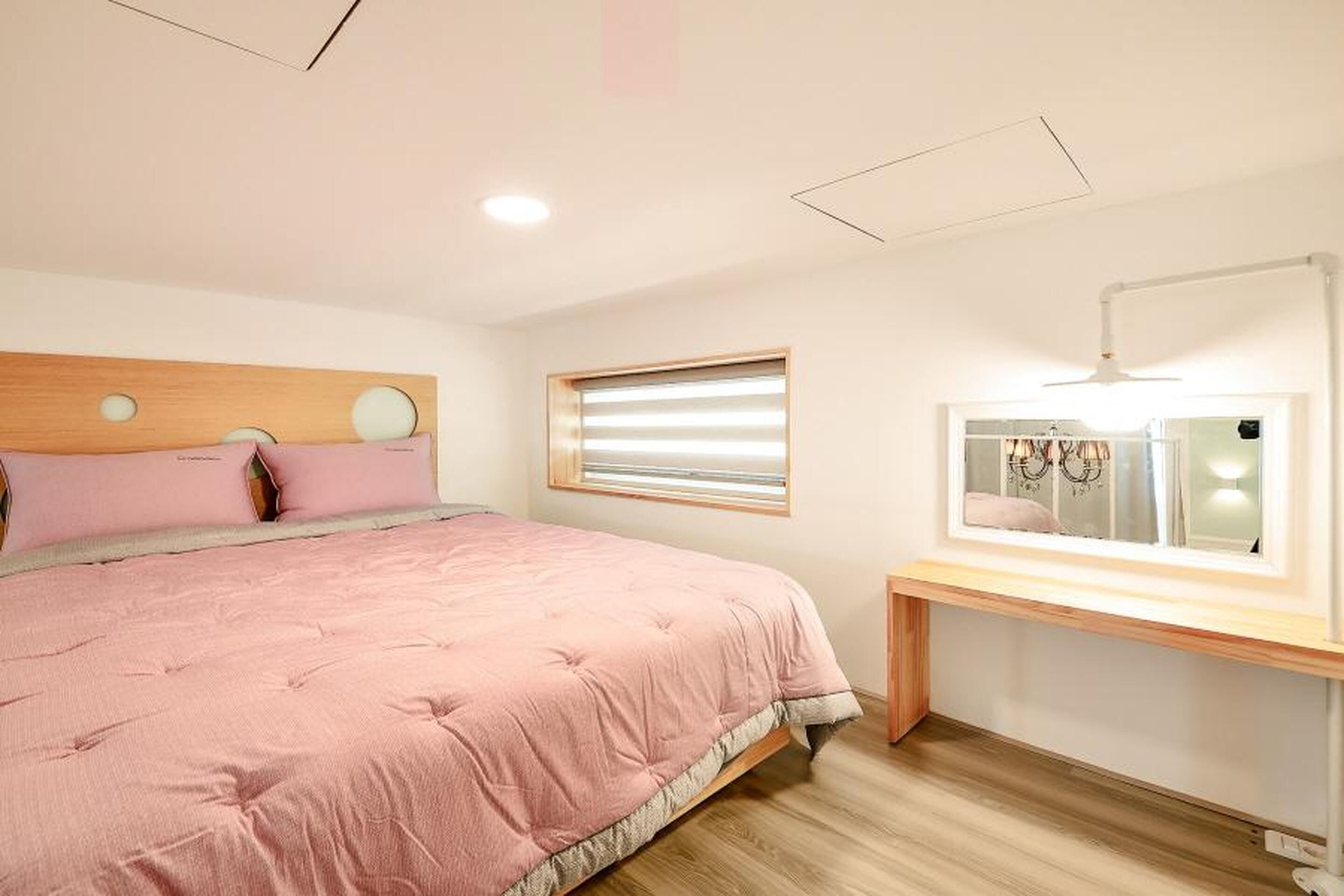 Un dormitorio con cama, mesita de noche, espejo y ventana con persianas.