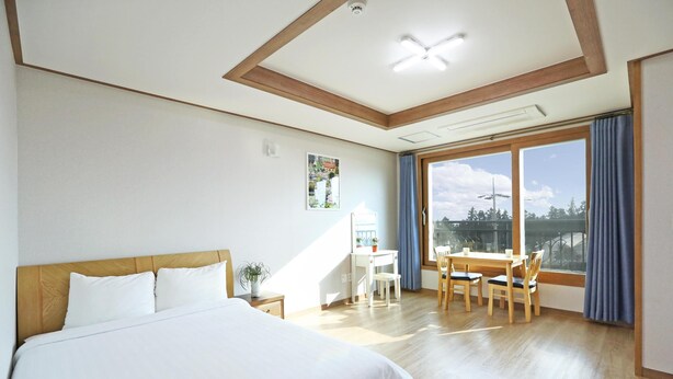 A hotel room with a large bed, a desk, and a view of the outdoors.