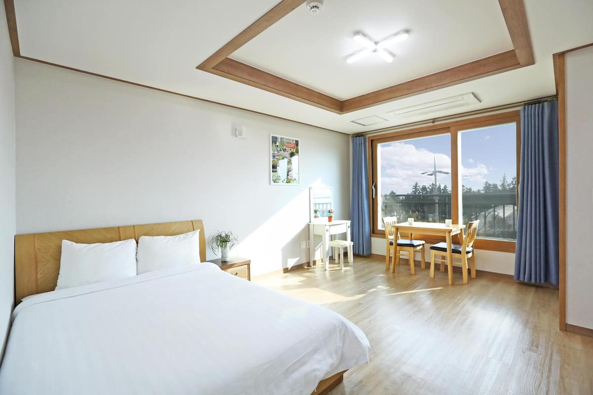 A hotel room with a large bed, a desk, and a view of the outdoors.