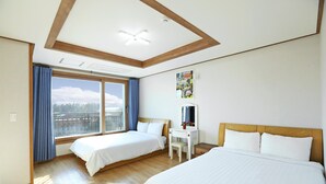A hotel room with two beds, a desk, a chair, and a large window with curtains.