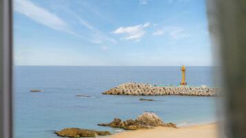 Un paysage côtier avec un phare sur une digue, une mer calme et des affleurements rocheux.