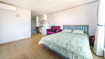 Una camera da letto con un letto, una sedia e una piccola cucina sullo sfondo.