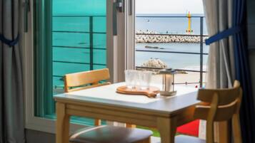 Una mesa con sillas y un juego de vasos, con vista a una costa rocosa y un faro.