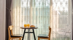 Una habitación con una mesa dispuesta para dos personas, con dos vasos de jugo de naranja y un plato con un pastel.