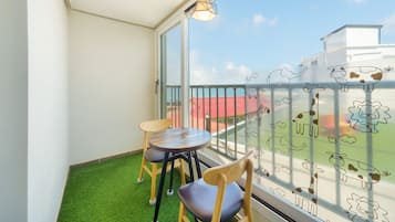 Ein Balkon mit Tisch und Stühlen, Blick aufs Meer und ein Belag aus künstlichem Rasen.